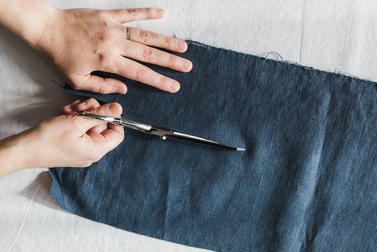 Ciseaux en denim avec une lame en tissu bleu foncé et des poignées en argent.